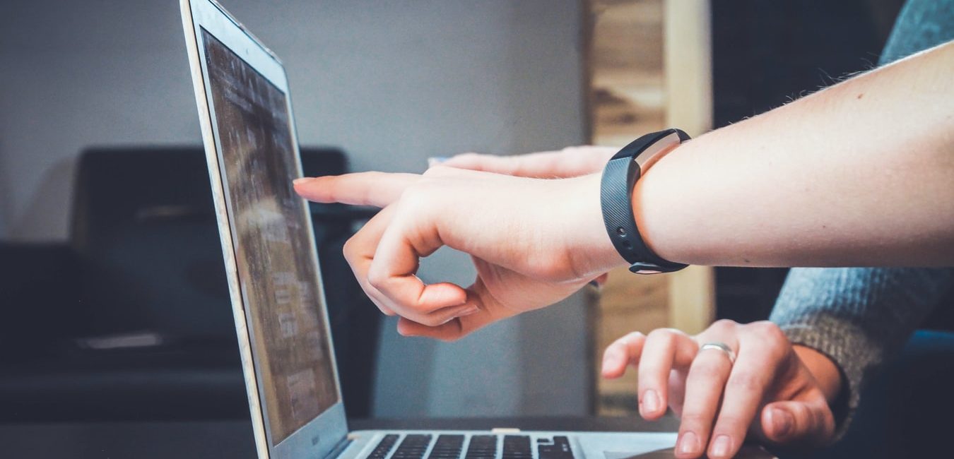 hand pointing to something on laptop screen